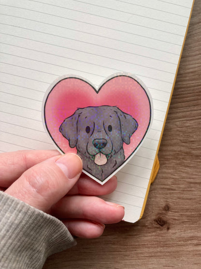 Heart-shaped sticker with a dog design held over a lined notebook