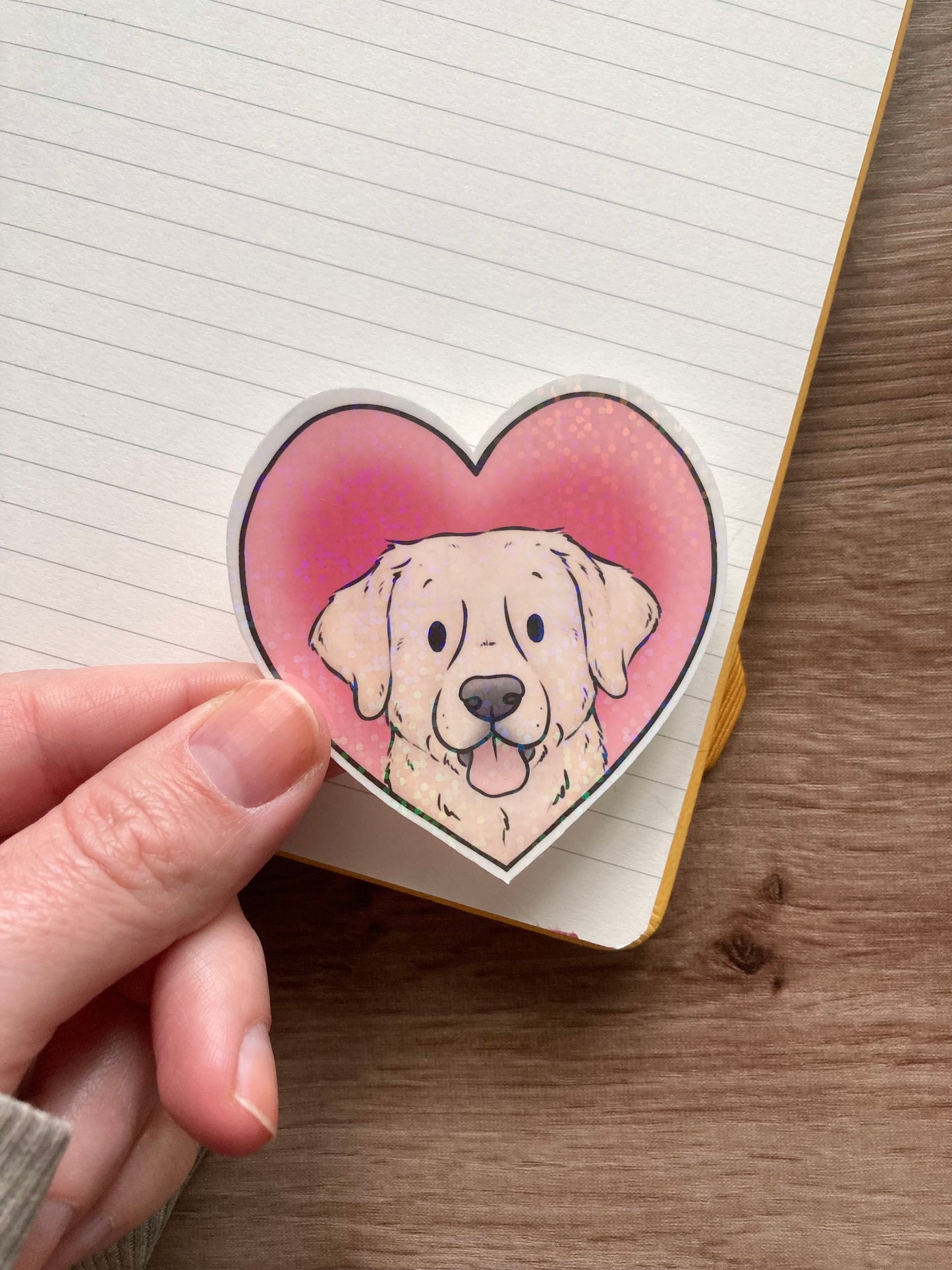 Heart-shaped sticker with a dog design held over a lined notebook
